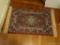 (UPHALL) SMALL AREA RUG; MACHINE MADE RUG IN HUES OF BURGUNDY, GREEN, NAVY AND CREAM. HAS FRINGE