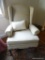 (FAM) WING BACK ARM CHAIR; BEIGE FABRIC ARMCHAIR WITH A WINGED BACK AND A CREAM THROW PILLOW. SITS