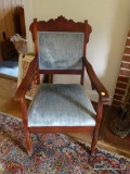 (FAM) WOODEN ARMCHAIR; ARMCHAIR WITH A BLUE FABRIC ALONG THE BACK AND SEAT. HAS FLORAL CARVINGS AND