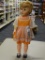 VINTAGE COLLECTIBLE DOLL; LARGE WIND-UP PLASTIC DOLL WITH BLOND HAIR AND ORANGE DRESS. NEAR THE