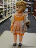 VINTAGE COLLECTIBLE DOLL; LARGE WIND-UP PLASTIC DOLL WITH BLOND HAIR AND ORANGE DRESS. NEAR THE