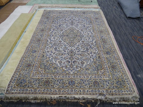 HAND KNOTTED AREA RUG; FLORAL AREA RUG IN HUES OF TAN, CREAM, BLUE, AND RED, WITH FRINGE ON BOTH