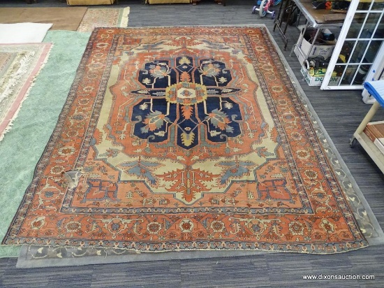 HAND KNOTTED AREA RUG; RED, CREAM, GREEN, AND BLUE AREA RUG WITH LARGE NAVY BLUE CENTER. HAS HOLE IN