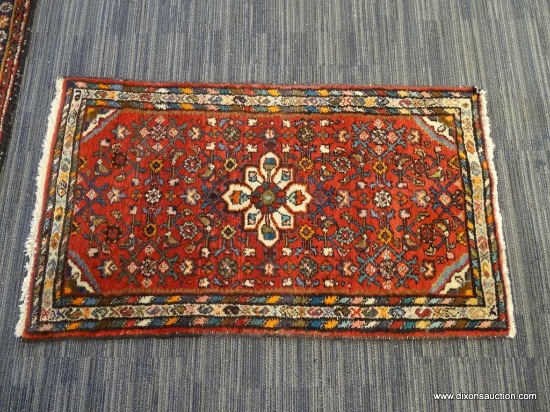 HAND KNOTTED RUG; RED RUG WITH ORANGE, BLUE, TEAL, AND CREAM COLORED FLOWERS. HAS FRINGE DETAILING