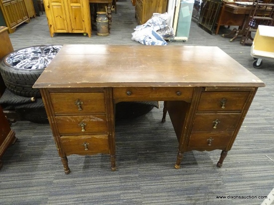 WOODEN DESK; WOOD GRAIN DESK WITH A MIDDLE DOVETAIL DRAWER THAT HAS METAL KNOBS ABOVE THE KNEE HOLE