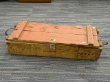 (R2) WOODEN AMMO CRATE; RED PAINTED AMMO CRATE WITH A LOCKING METAL LATCH AND WRITING ON THE SIDE.