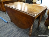 (R4) DROP LEAF TABLE; RECTANGULAR TABLE WITH 2 SIDE LEAVES. SITS ON TURNED LEGS. MEASURES 3 FT 9.5