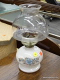 (R4) CERAMIC OIL LAMP; HAND PAINTED CERAMIC OIL LAMP WITH A WHITE BASE THAT HAS FLOWERS PAINTED ON