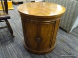 (R4) ROUND END TABLE; WOODEN END TABLE WITH A DRUM BASE. HAS A ROUNDED CABINET DOOR WITH A METAL