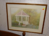 (R6) FRAMED LANDSCAPE PRINT; THIS PIECE SHOWS A GAZEBO IN A PARK WITH A BIKE IN FRONT OF IT. SIGNED