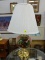 (R5) TABLE LAMP; PAINTED CHERRY ON A BELL SHAPED LAMP WITH A BRASS BOTTOM AND COMES WITH A COOLIE