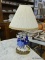(R5) TABLE LAMP; VICTORIAN COUPLE DANCING CERAMIC TABLE LAMP ON A BRASS STAND WITH HOLES IN IT.