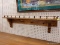 (R6) WALL HANGING COAT RACK; WOODEN WALL HANGING COAT RACK WITH A SHELF AND A RAILING AROUND THE