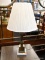 (R2) TABLE LAMP; WHITE MARBLE BASE TABLE LAMP WITH A FADED BRASS STEM. COMES WITH A CREAM COOLIE