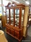 (R2) GLASS FRONT CHINA CABINET; 2 PC CHINA CABINET WITH A BEAUTIFUL CARVED BROKEN ARCH PEDIMENT TOP