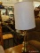 (R3) TABLE LAMP; BRASS TURNED TABLE LAMP THAT COMES WITH A WHITE WITH BROWN LINES, DRUM LAMP SHADE.