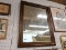 (WALL) WALL HANGING MIRROR; MIRROR SITS IN A THICK WOODEN FRAME. MEASURES 32 IN X 41.5 IN.