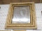 (WALL) WALL HANGING MIRROR; MIRROR SITS IN A REEDED FRAME WITH LEAF CARVED DETAILING. MEASURES 25 IN