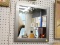(WALL) WALL HANGING MIRROR; SQUARE MIRROR, SITS IN A SILVER FINISHED FRAME. MEASURES 16 IN X 16 IN.