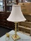 (R2) TABLE LAMP; TURNED METAL TABLE LAMP WITH A BRUSHED BRASS FINISH AND A WHITE COOLIE LAMP SHADE.