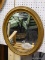 (WALL) WALL HANGING MIRROR; OVAL MIRROR THAT SITS IN A BRONZE FINISHED WOODEN FRAME. MEASURES 20 IN