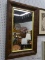 (WALL) WALL HANGING MIRROR; MIRROR SITS IN A BRASS TONED FRAME AND WOODEN FRAME. MEASURES 25.25 IN X