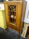 (R1) DISPLAY CABINET; WOODEN DISPLAY CABINET WITH A ROUNDED TOP AND REEDED DETAILING DOWN THE SIDES.