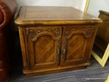 (R1) END TABLE; WOODEN END TABLE WITH A SCALLOP EDGE TOP AND 2 FRONT CABINET DOORS WITH CARVED LEAF
