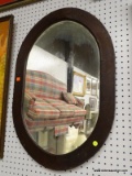 (WALL) WALL HANGING MIRROR; OVAL SHAPED WALL HANGING MIRROR IN A DARK STAINED WOODEN FRAME. MEASURES