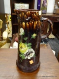 (R2) BROWN BENNINGTON GLAZE PITCHER; HAS HAND PAINTED FLORAL ACCENTS. MEASURES 12.5 IN TALL.