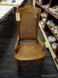 (R1) VINTAGE VICTORIAN STYLE SEWING ROCKER; HAS SCROLL ARMS AND A CANE SEAT AND BACK. IS IN GOOD