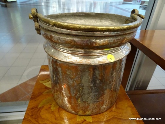 (WINDOW) HAMMERED COPPER BUCKET; HAS A BRASS HANDLE. MEASURES 10.25 IN TALL WITH A 10.5 IN DIAMETER.