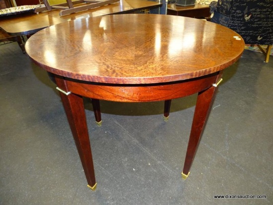 (R1) ROUND TABLE; WOODEN TABLE WITH FOUR TAPERED BLOCK LEGS, THAT HAVE BRASS CAPPED FEET. HAS A 35.5