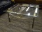 (R4) GLASS TOP COFFEE TABLE; HAS A BEVELED AND CUT CORNER GLASS TOP SITTING ON A SILVER FRAME WITH