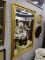 (LWALL) WALL HANGING MIRROR; BEVELED GLASS MIRROR SITTING IN A GOLD TONE FRAME WITH SCROLLING