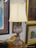 TABLE LAMP; CLEAR GLASS TABLE LAMP WITH LAYERED SHELL PATTERN. COMES WITH CREAM OVAL SHADE.