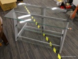 (R2) ENTERTAINMENT STAND; GLASS TOP, 3-TIERED ENTERTAINMENT STAND WITH A SILVER METAL FRAME.