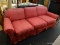 (R4) 3-CUSHION SOFA; ROLL ARM, 3-CUSHION SOFA WITH A PINKISH RED SLIPCOVER WITH CUSHIONS. MEASURES 7