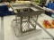 (R10) OUTDOOR LAMP HOUSING; METAL ENCASING SHADE FOR OUTDOOR CEILING LAMP. MEASURES 10 IN X 10 IN X