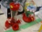 (R11) PAIR OF HUMMINGBIRD FEEDERS; TWO GLASS AND PLASTIC HUMMINGBIRD FEEDERS WITH RED BASES. ONE HAS