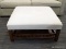 MODERN OTTOMAN; OFF WHITE/CREAM UPHOLSTERED, SQUARE OTTOMAN WITH A BLOCK LEGS LEADING TO A LOWER