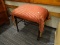 MAHOGANY VANITY BENCH WITH A UPHOLSTERED SEAT AND TASSELS.