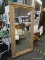 LARGE BEVELED GLASS MIRROR; MIRROR SITS IN A GOLD PAINTED WOODEN FRAME WITH WORN FINISH RELIEF AND