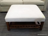 MODERN OTTOMAN; OFF WHITE/CREAM UPHOLSTERED, SQUARE OTTOMAN WITH A BLOCK LEGS LEADING TO A LOWER