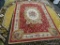 ROYALTY AREA RUG; WOOL PILE AREA RUG WITH A FLORAL PATTERN AND A RED WITH BEIGE COLOR. MEASURES 5 FT