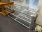 (WINDOW) TV STAND; THREE TIERED GLASS TOP MODERN TV STAND. HAS A SILVER FRAME. MEASURES 50 IN X 23.5