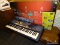 (R4) YAMAHA PSR-270 PORTABLE, ELECTRONIC, GRAND PIANO KEYBOARD. COMES IN ORIGINAL BOX WITH STAND.