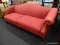 (R1) CAMELBACK SOFA; HAS ROLLING ARMS AND A REDDISH PINK UPHOLSTERY WITH A DIAMOND SHAPED PATTERN.