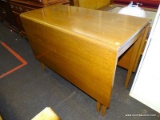 (R2) DROP LEAF TABLE; WOODEN TABLE WITH TWO 20.5 IN LEAVES AND SITTING ON TAPERED BLOCK LEGS.