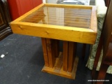 (R1) RUSTIC SIDE TABLE; HAS A FOG GLASS SHEET SITTING ON A WOOD PANELED TOP. MEASURES 24.25 IN X